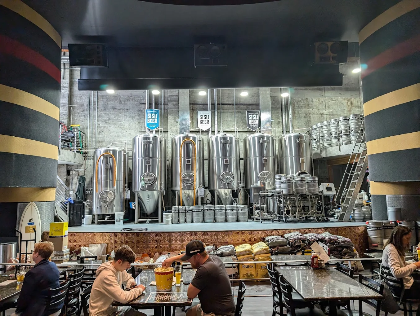 Guests dining in front of the brewery tanks at the Times Theater taproom