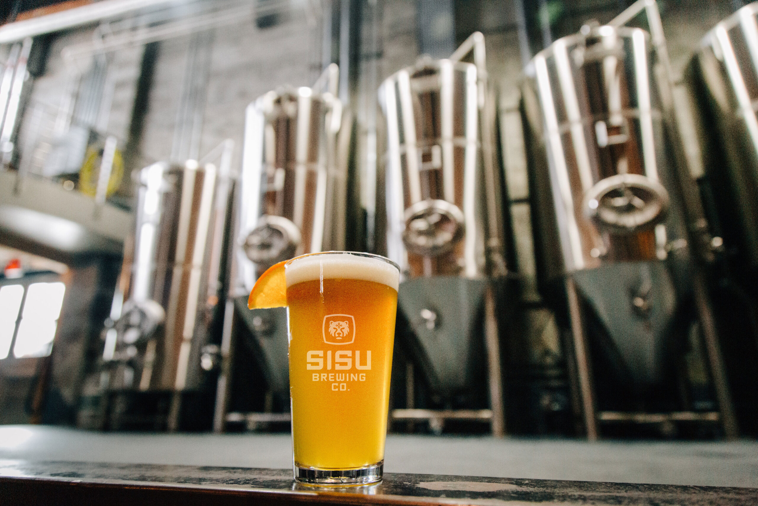 Sisu Beer pint in front of the stainless brewhouse tanks in Seaside