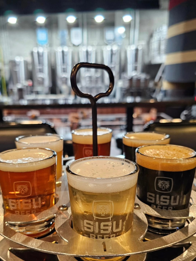 Sisu Brewing Co beer flight Flight of Sisu Brewing Co beers on a serving tray with brewery tanks behind