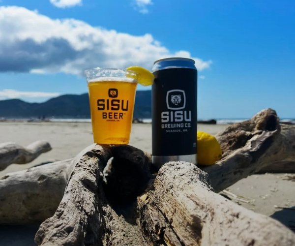 Sisu Beer pint and can on driftwood at the beach on the Oregon Coast